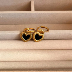 Gold heart-shaped rings with black centers on a beige surface