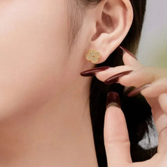 Close-up of a person wearing a gold earring with a blurred background