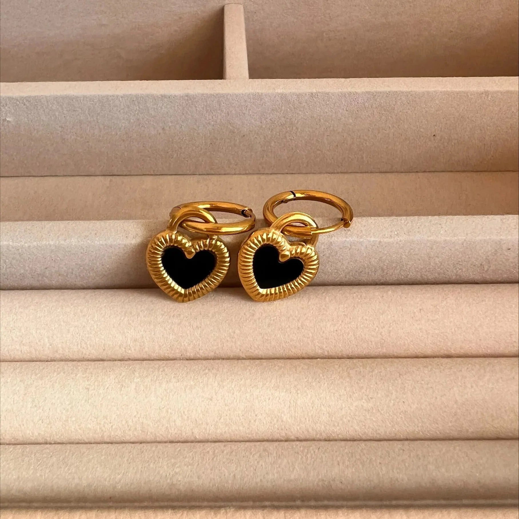 Gold heart-shaped rings with black centers on a beige surface
